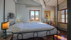 Une chambre à coucher avec un lit, une table de chevet, une lampe, une fenêtre et un tableau au mur.