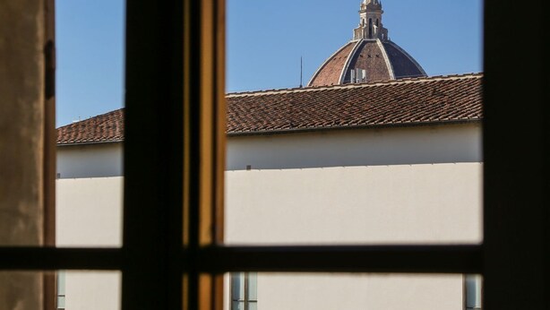 Une vue à travers la fenêtre d’un bâtiment doté d’un toit en tuiles et d’une structure en forme de dôme.