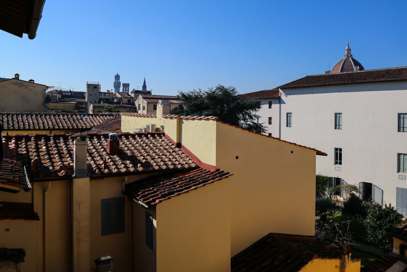 A courtyard with a tiled roof, a building with a dome, and another with a bell tower.