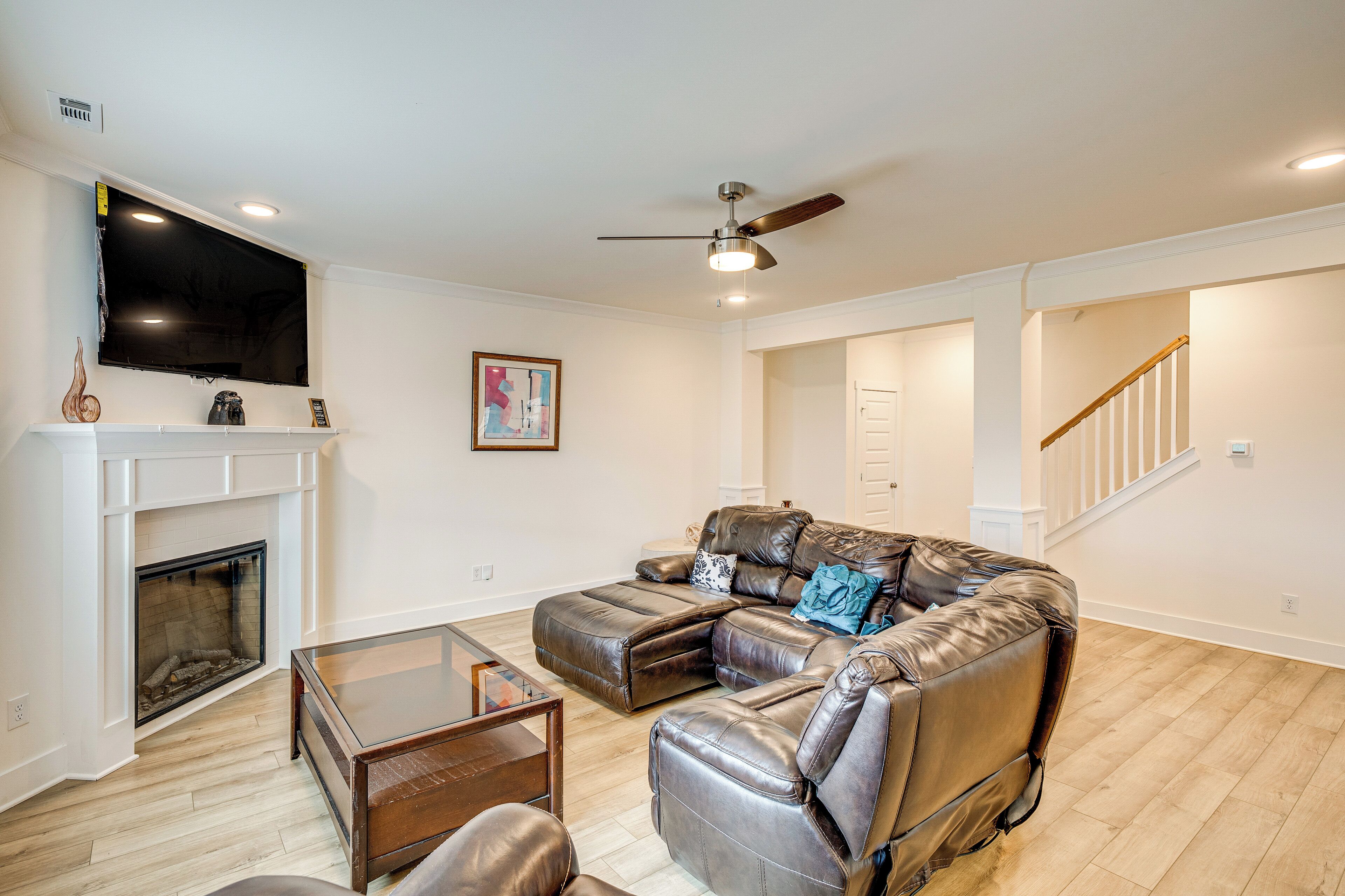A living room with a fireplace, leather sofa, and a flat-screen TV.