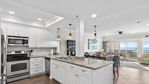 A modern kitchen with white cabinetry, a granite countertop, and a large island.