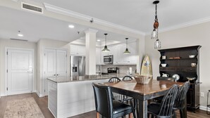 A modern kitchen with white cabinetry, a wooden island, and black bar stools.