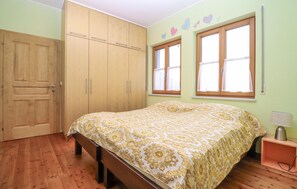 A bedroom with a bed, wooden wardrobe, two windows with curtains, and a nightstand with a lamp. - Ferienwohnung in Stratzing (Stratzing bei Krems)