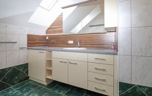 A modern bathroom with a skylight, a sink with a wooden backsplash, and marble flooring. - Ferienwohnung in Stratzing (Stratzing bei Krems)