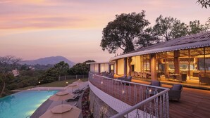 A resort with a swimming pool, outdoor seating, and a dining area with a view of the mountains. - Naukuchia House, Naukuchiatal - IHCL SeleQtions (Nainital)