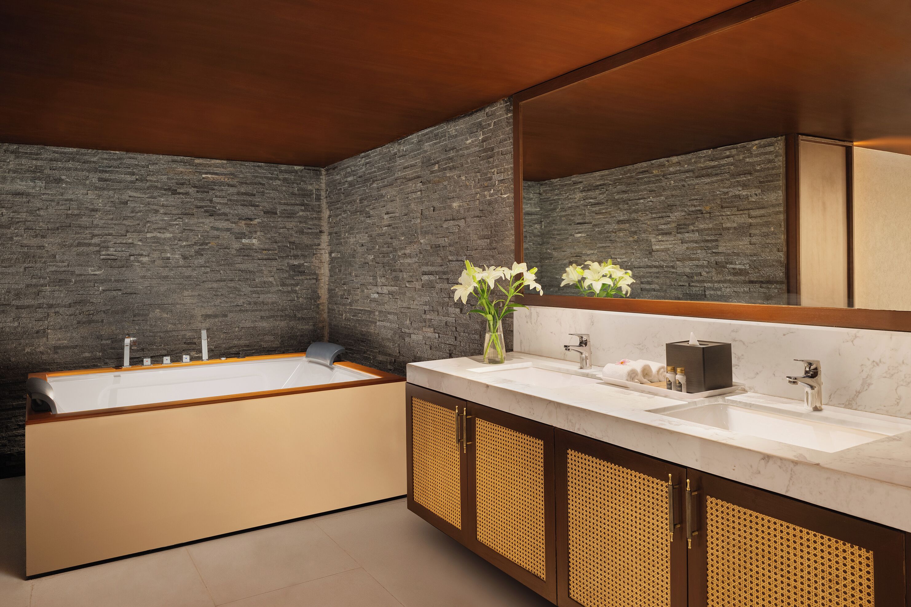 Un baño moderno con una bañera grande, dos lavamanos y un espejo.