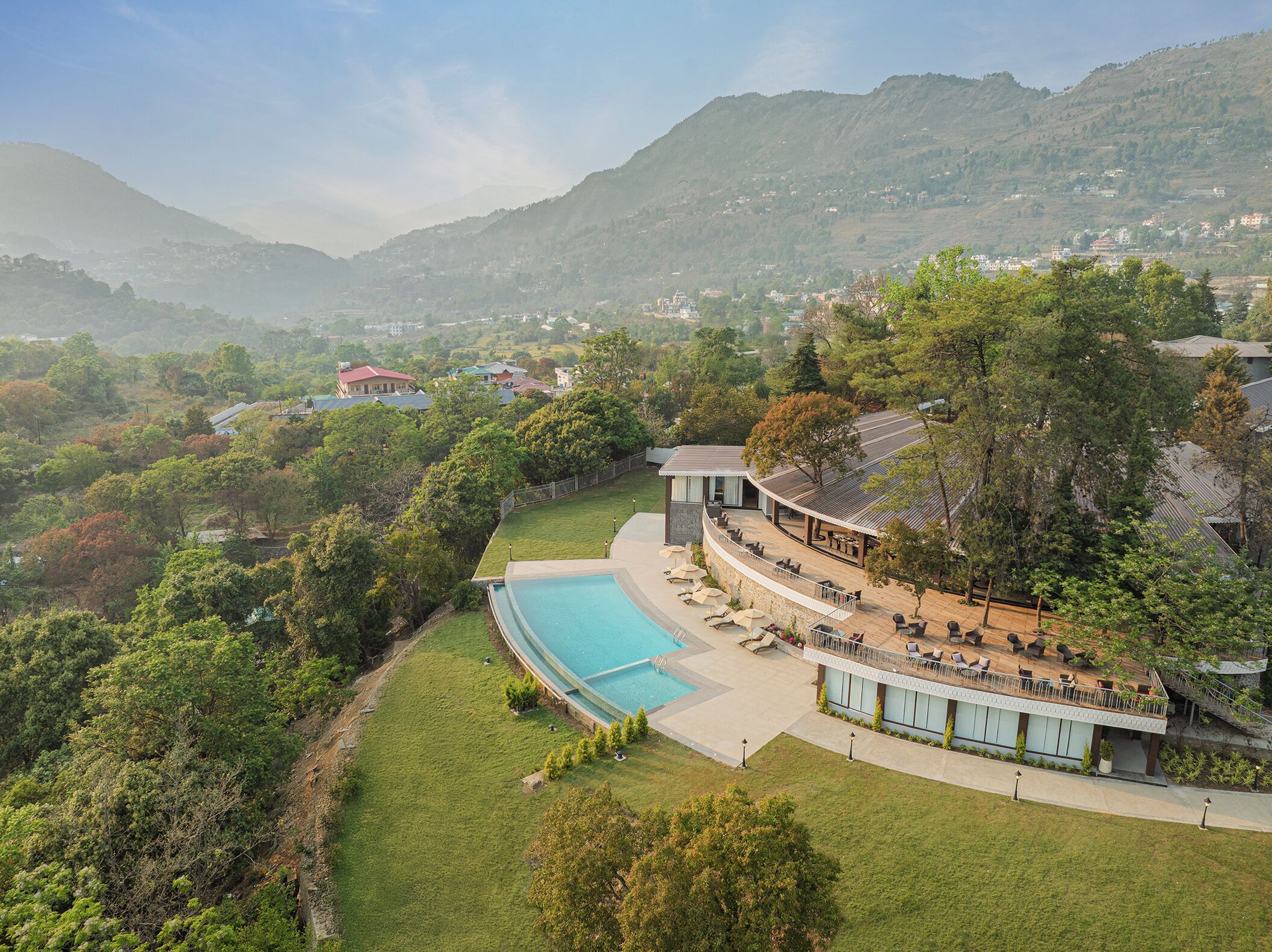 A resort with a pool, outdoor seating, and a view of the surrounding hills.
