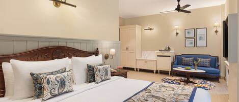 A hotel room with a large bed, a sofa, a desk, and a ceiling fan.