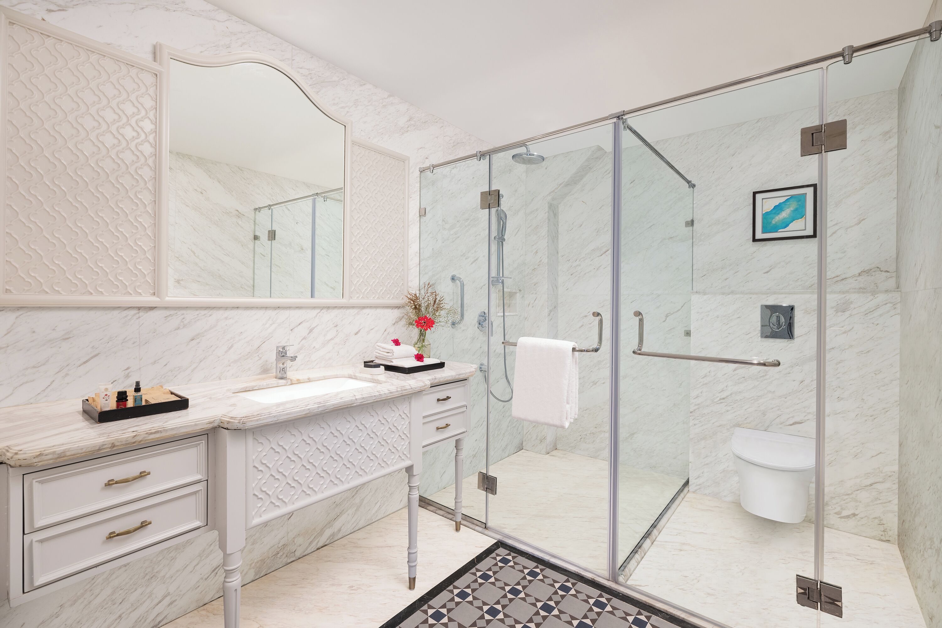 A modern bathroom with a marble vanity, a glass shower enclosure, and a white toilet.