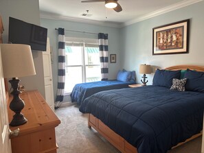 A bedroom with two beds, a wooden dresser, a ceiling fan, and a painting on the wall. - Ocean View 4BR-4BA - Beach Access & Pool + Linens - Pet Friendly (Ocean Isle Beach)