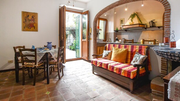 Un soggiorno accogliente con un divano, un tavolo da pranzo con sedie e un angolo cucina con un arco in mattoni.