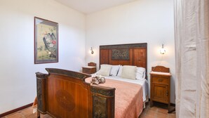 Una camera da letto tradizionale con un letto di legno, un comodino, una lampada a parete e un'opera d'arte incorniciata.