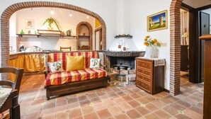 Un soggiorno accogliente con un divano, un caminetto e una cucina sullo sfondo.