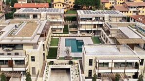 A modern residential complex with multiple buildings, a central swimming pool, and solar panels on the rooftops.