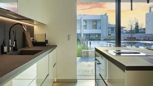 A modern kitchen with a large window, a view of buildings, and a minimalist design.
