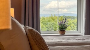 A bedroom with a large window, a bed, a bedside table, and a potted plant. - High House, Southwaite -  a cottage that sleeps 10 guests  in 5 bedrooms (Southwaite)