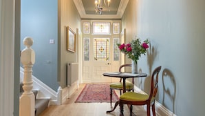 A hallway with a staircase, a chandelier, a door with stained glass, and a table with chairs. - High House, Southwaite -  a cottage that sleeps 10 guests  in 5 bedrooms (Southwaite)