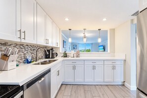 A modern kitchen with white cabinets, stainless steel appliances, and a tiled backsplash.