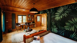 A wooden cabin interior with a bed, a dining area, and a large window. - Enchanted Lodge 2 Great Ayton Yorkshire - sleeps 2 guests  in 1 bedroom (Great Ayton)