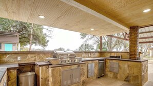 Una cocina exterior con una parrilla empotrada y armarios de almacenamiento.