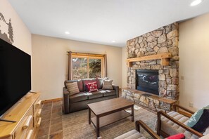 A cozy living room with a stone fireplace, a large window, and a flat-screen TV. - Cf13k-3 (Keystone)