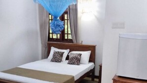 A single bed with a wooden frame, a bedside table, a lamp, and a window with curtains. - Sanduhan Villa, Stay in Sri Lanka! (Warakapola)