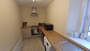 A compact kitchen with a built-in oven, a microwave, and a toaster. There's a window with a view of the outside. - Ye Olde Hotel (St. Andrews)