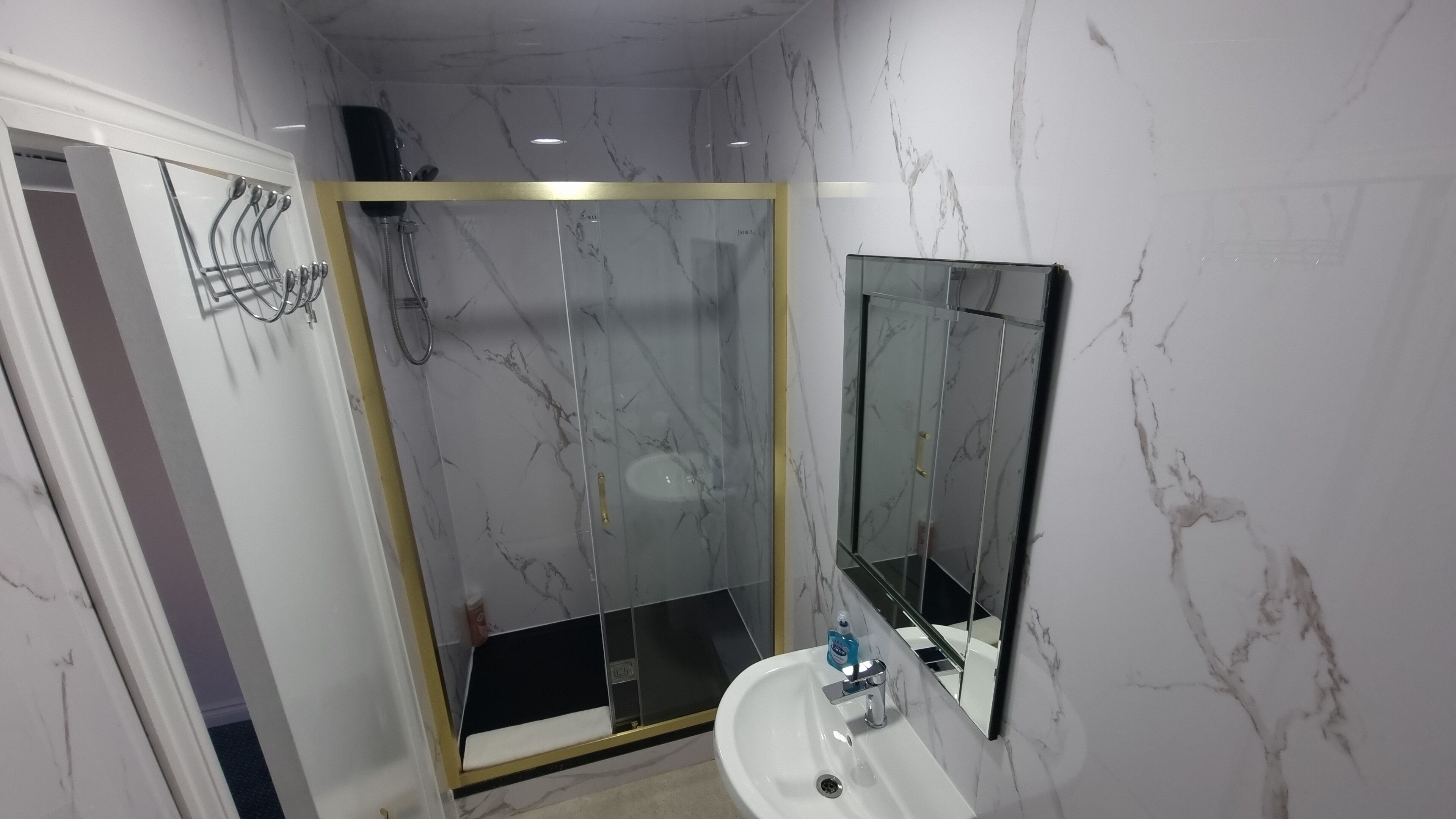 Een badkamer met een glazen douchecabine, een wastafel en een spiegel.