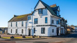 A white building with a black roof, multiple windows, and a sign that reads "Ye Olde Hotel". - Ye Olde Hotel (St. Andrews)