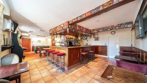 A bar area with stools, a counter, and a fire exit sign. - Ye Olde Hotel (St. Andrews)