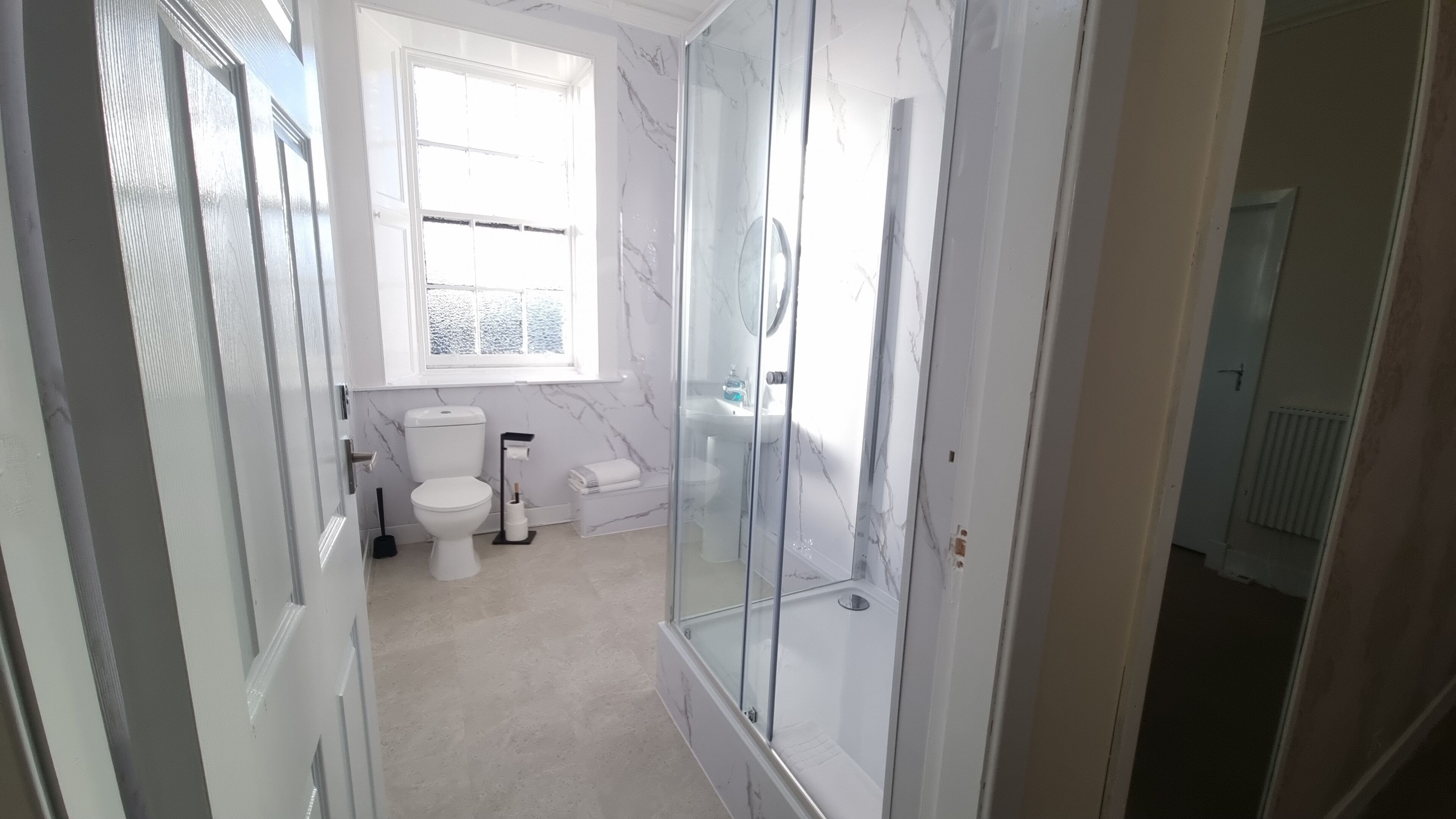 Un baño moderno con cabina de ducha de vidrio, inodoro y lavamanos.