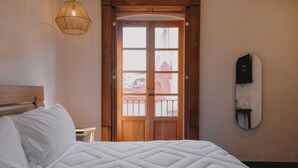 A bedroom with a bed, wooden door, and a wall-mounted mirror. - Hotel Boutique Casa Yága (Querétaro)