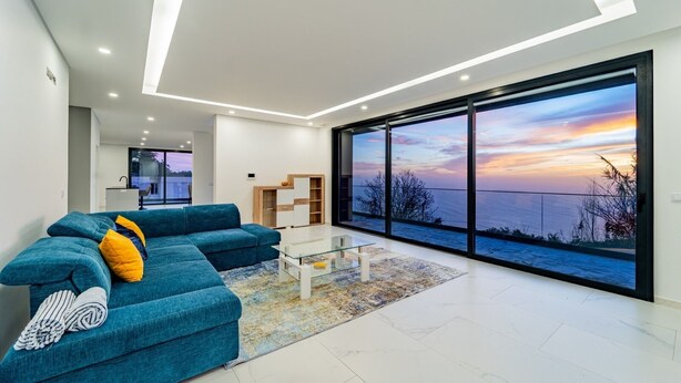 Een moderne woonkamer met een groot raam, een blauwe bank en een glazen salontafel.