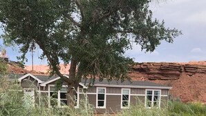 Ein Haus mit einem großen Baum davor, umgeben von hohem Gras.