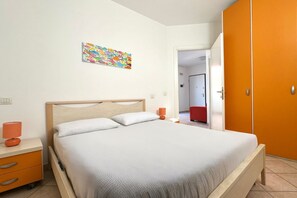 A bedroom with a bed, a nightstand, a lamp, a wardrobe, and a colorful artwork on the wall. - P045 – Porto Recanati, splendid three-room apartment 300 meters from the sea (Porto Recanati)