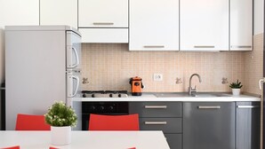 Una cocina moderna con alacenas blancas, un refrigerador de acero inoxidable, una estufa a gas y un lavamanos.
