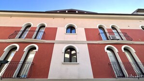 Un edificio con fachada roja y blanca, varios balcones con barandillas negras y ventanas arqueadas.