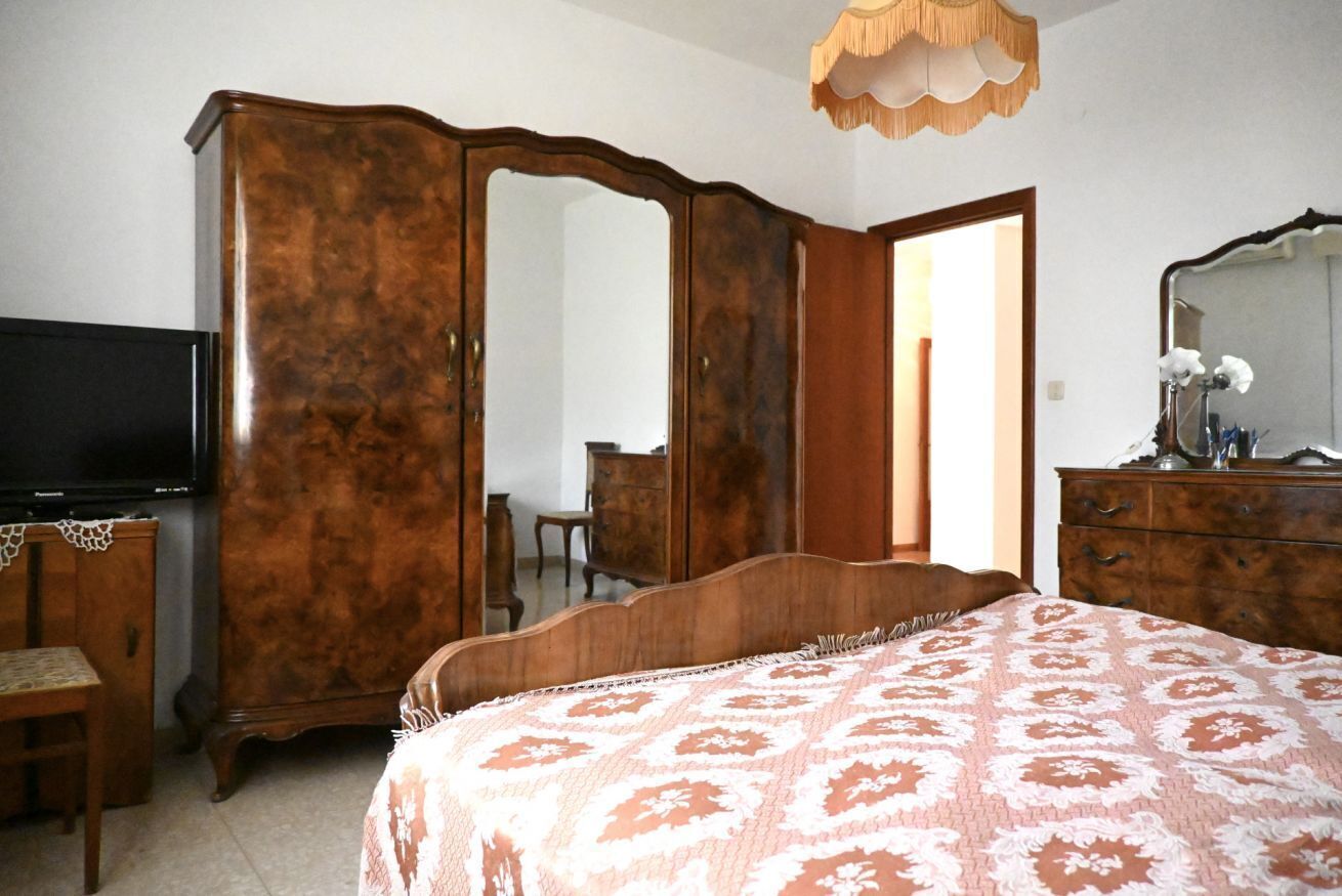 Une chambre à coucher avec un lit, une armoire, une télévision et un miroir.