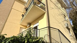 Un edificio a più piani con balconi, condizionatori e cielo sereno.