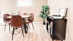 Un comedor moderno con una mesa redonda, cuatro sillas marrones, una planta en maceta y un tocadiscos en un estante.