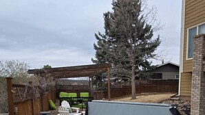 Un jacuzzi en una terraza de madera, con un cerco de madera y un árbol al fondo.