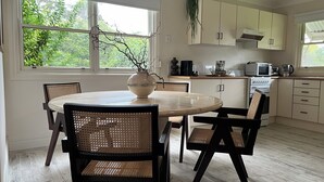 Une cuisine moderne avec des meubles blancs, une table de salle à manger ronde et des chaises en osier.