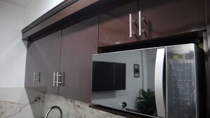 Une cuisine avec des meubles de couleur sombre, un réfrigérateur en acier inoxydable et un plan de travail en marbre.