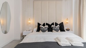 A modern hotel room with a large bed, two bedside tables, a mirror, and a wall-mounted light fixture. - La Brisa | Pool - terrace - gym (Estepona)