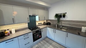 Una cocina moderna con gabinetes grises, un lavamanos de acero inoxidable y un horno empotrado.