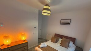 Un dormitorio con cama, mesitas de noche y dos lámparas de pared.