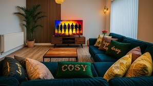 Una sala de estar moderna con televisor, sofá y almohadones decorativos.