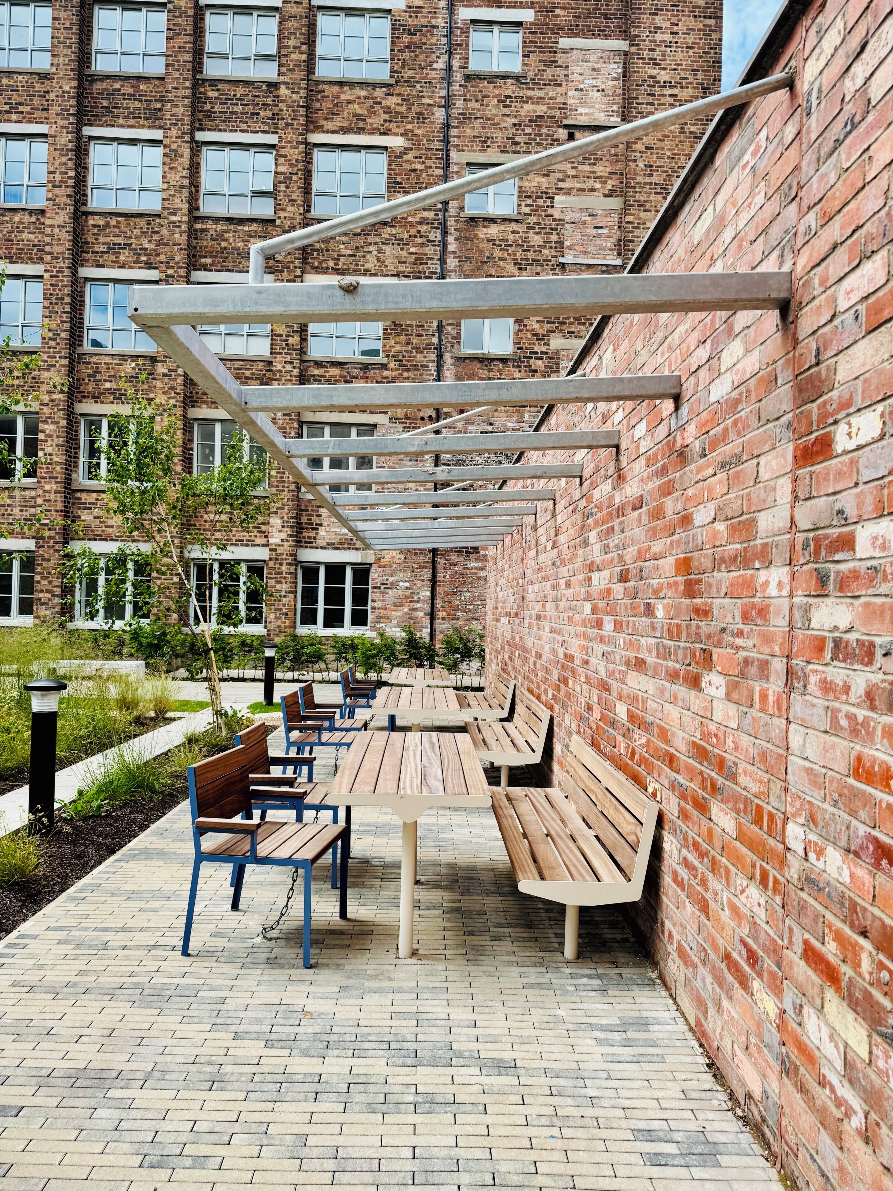 A courtyard with outdoor seating, brick walls, and a building with multiple windows in the background.
