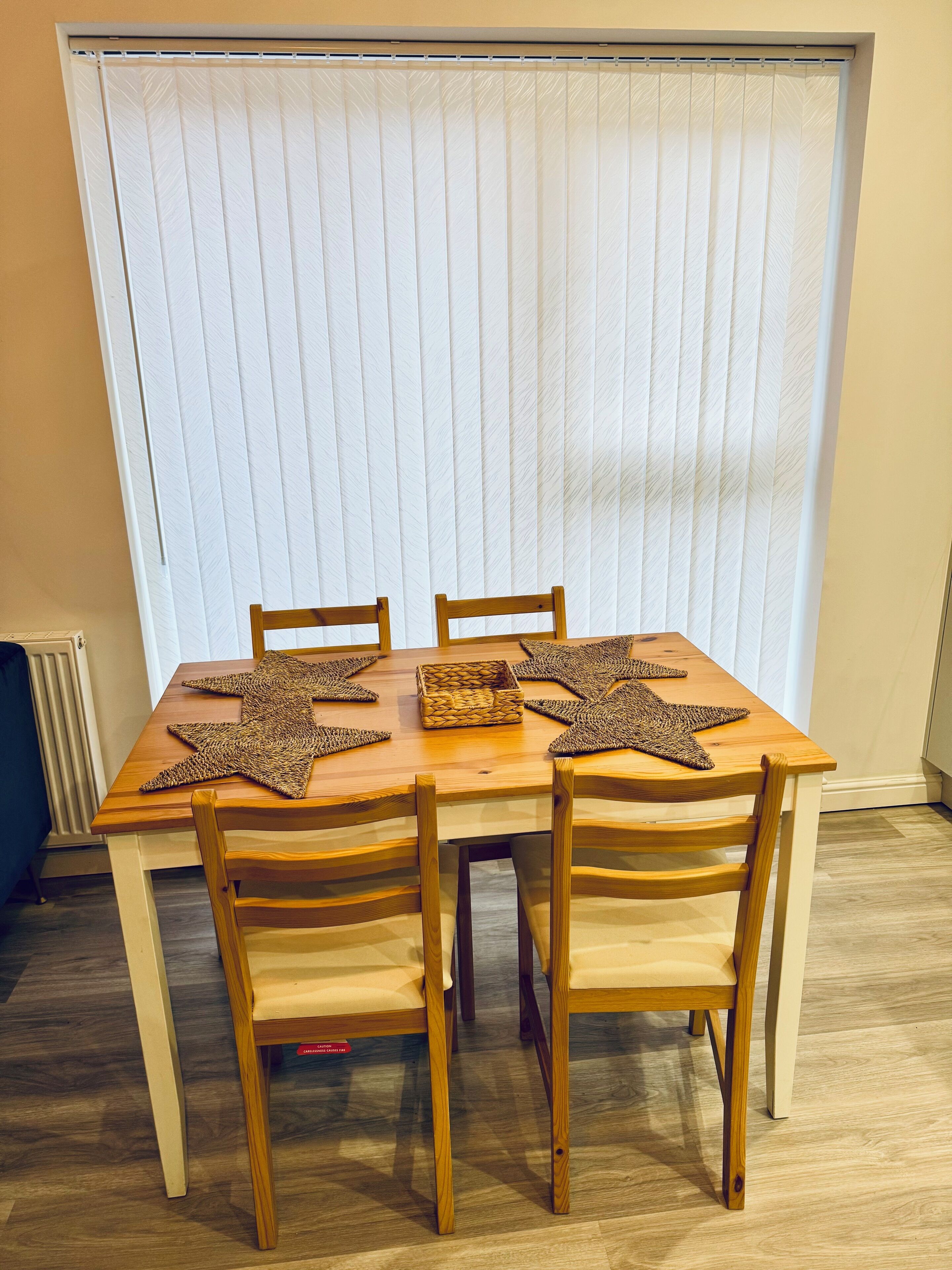 A dining table with four chairs, star-shaped placemats, and a woven basket.
