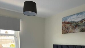 A hotel room with a neatly made bed, a painting on the wall, and a window with a view. - Glass Street Apartment (Glenrothes)